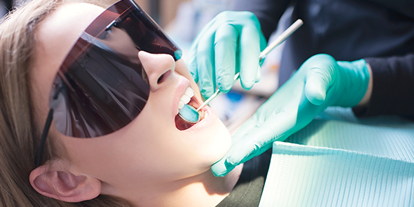 Young woman with protective dark glasses having dental work performed.