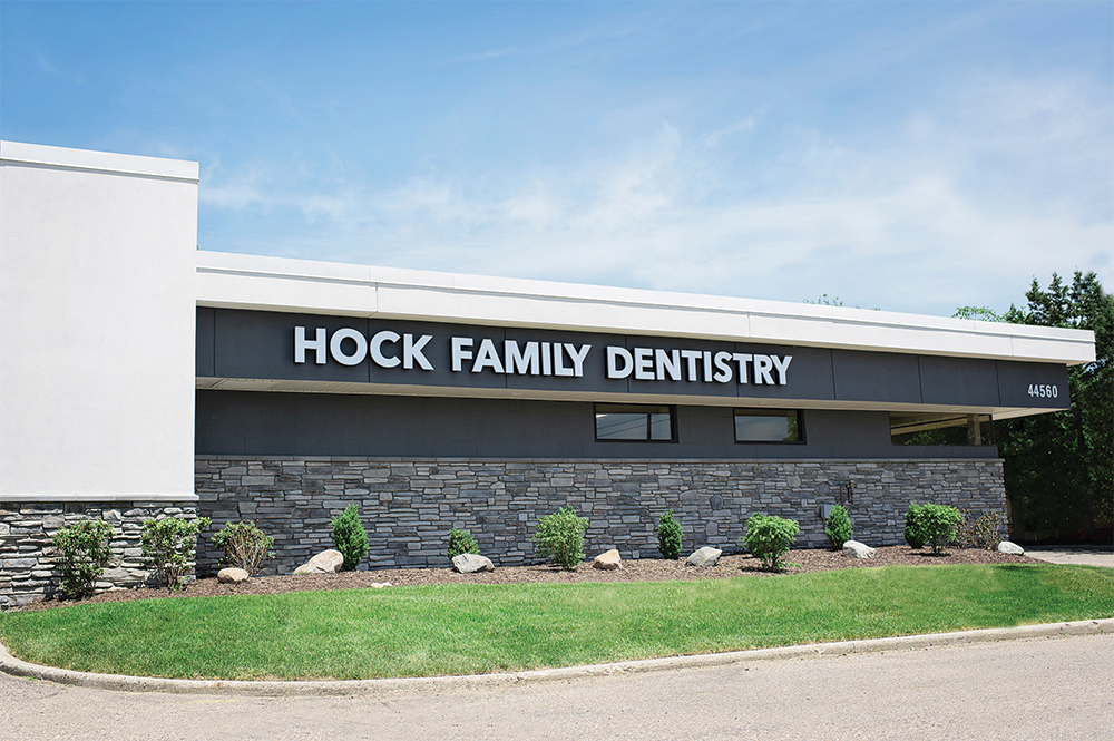 Outdoor photo of a building with gray brick and a sign that says "Hock Family Dentistry"